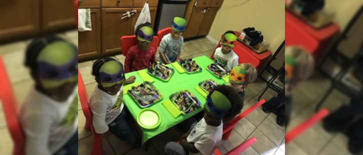 Children sitting down on table wearing mask